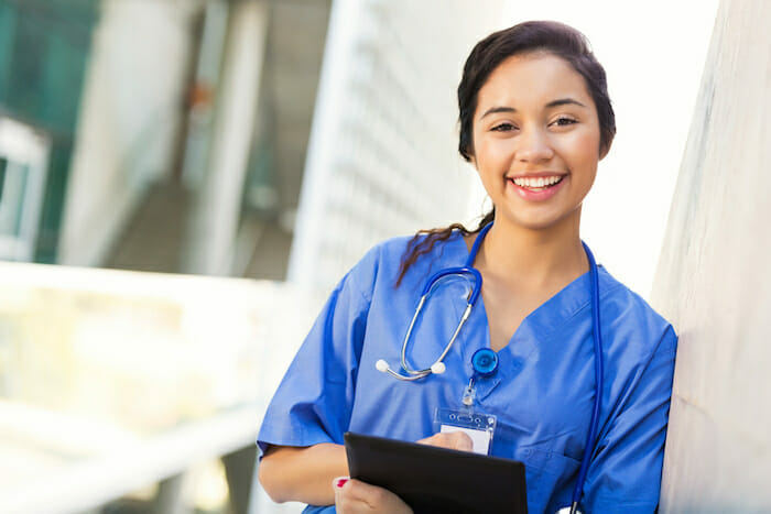 Smiling nurse with clipboard and documents.