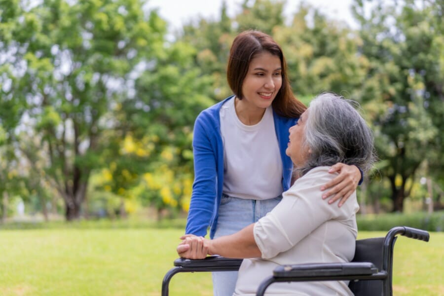 caregiver pushing a patient with alzheimer's disease in a wheelchair