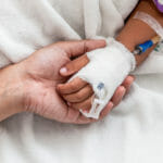 mother holding child's hand who have IV solution