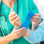 Nurse wrapping bandage on the wrist of injured senior adult