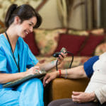 Home healthcare nurse checks patient's blood pressure