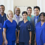 nurses in royal blue scrubs and stethoscopes around neck and some doctors in suits