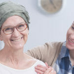 younger woman holding shoulders of middle aged woman with headwrap and glasses