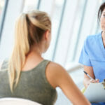 nurse with clipboard talking to girl