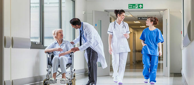 a hallway of a hospital with nurses, a doctor and patient