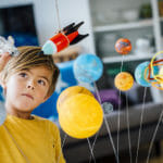 Little boy playing with solar system in classroom.