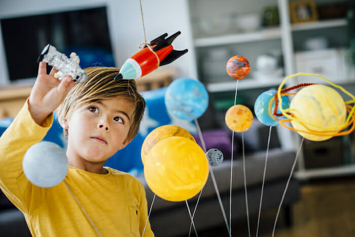 Little boy playing with solar system in classroom.