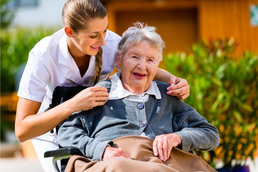 An older woman suffering from multiple sclerosis with a caretaker