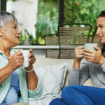 mature lady and granddaughter enjoying coffee on a couch