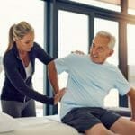 Adult man undergoing physical therapy program with his physical therapist