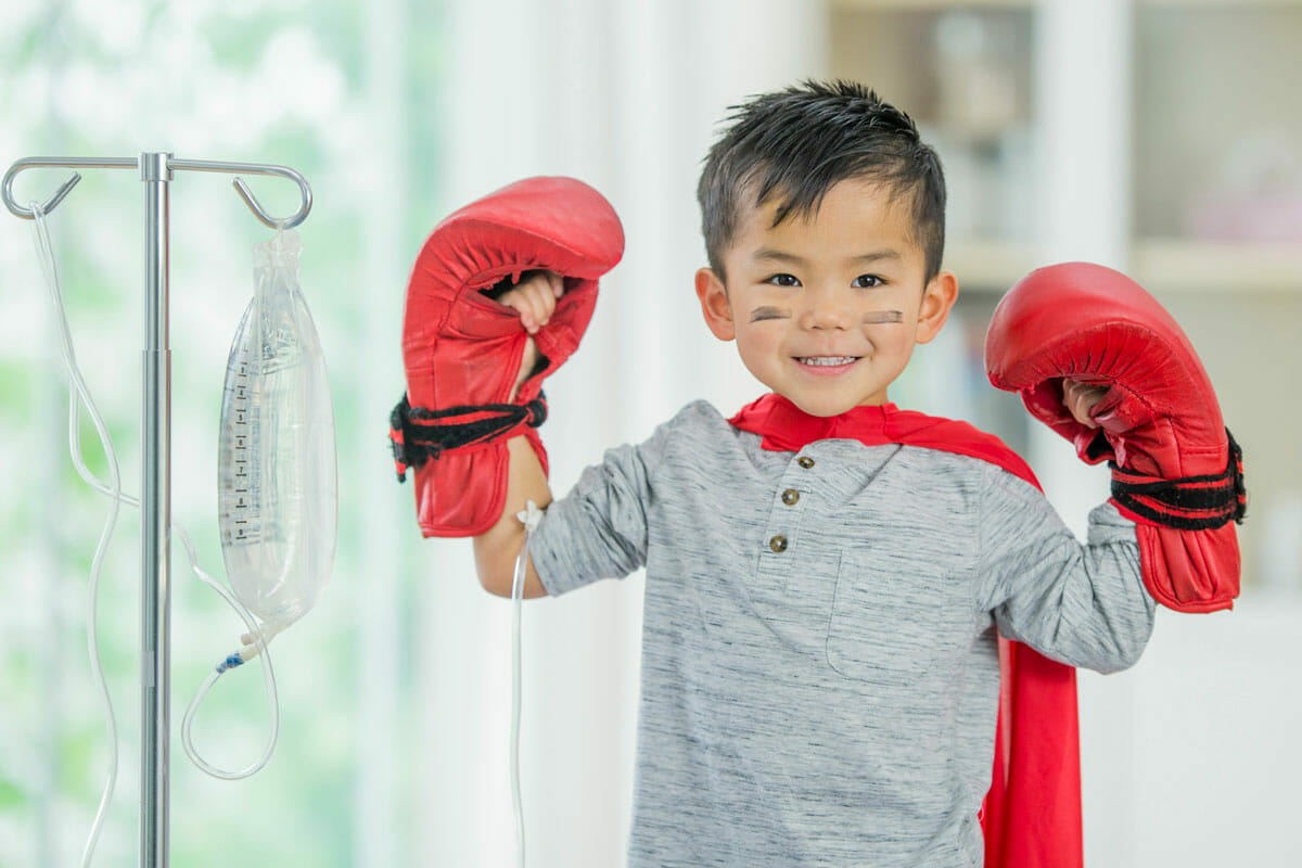 young boy wearing boxing gloves and hooked to a hanging bag via iv