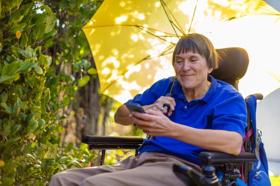 an individual with MS using an umbrella to shield the sun