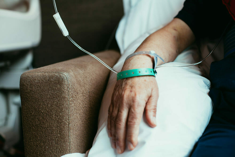 man sitting in chair with iv running out of arm