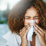 woman-sneezing-into-tissue