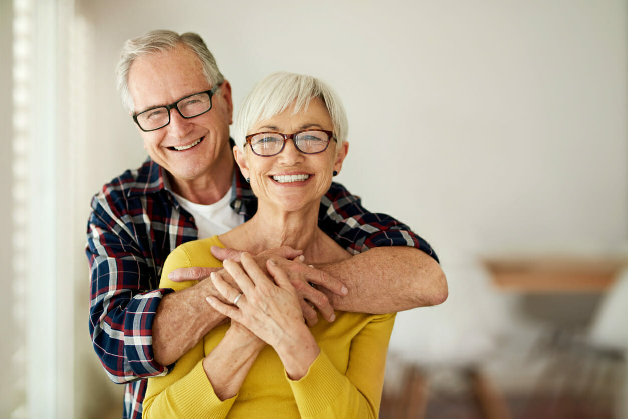 senior man and woman hugging and smiling