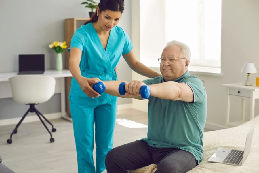 Home nurse helping a patient lift weights