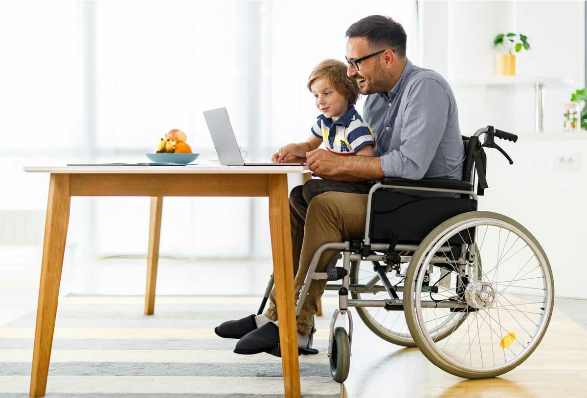 father sitting in rental wheelchair with son in his lap