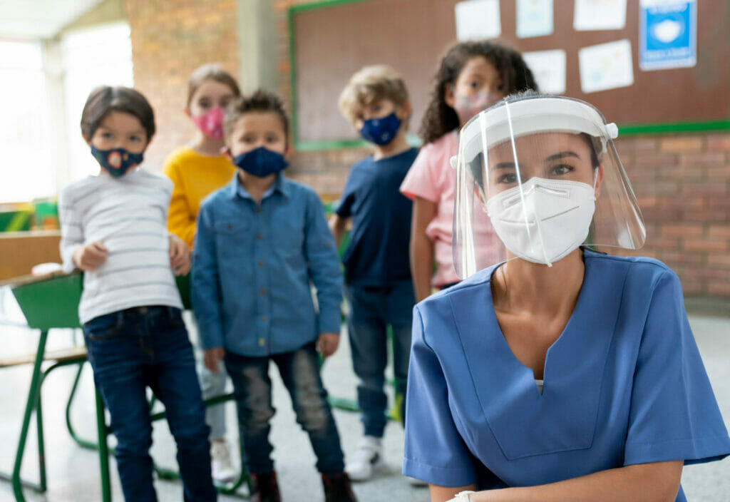 SSchool nurse during the COVID-19 pandemic surrounded by kids wearing facemasks
