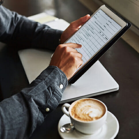 person completing form on tablet at cafe