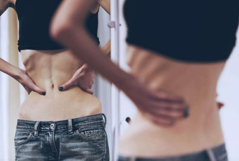 a woman suffering from anorexia looking in the mirror