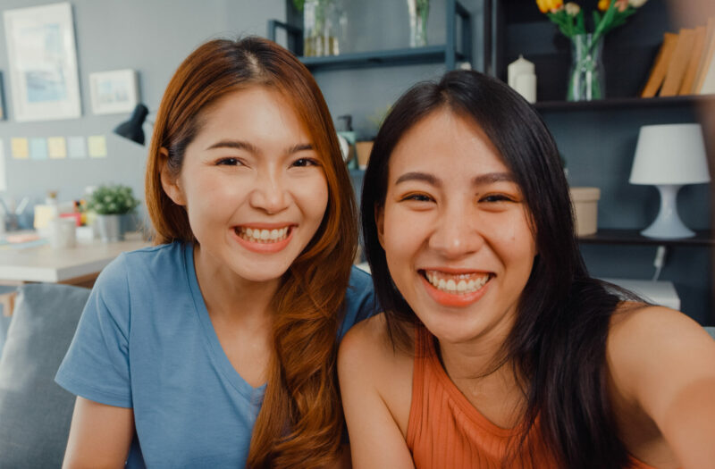 Asian women feeling happy smiling selfie and looking to camera while relax in living room at home. Cheerful Roommate ladies video call with friend and family, Lifestyle woman at home concept.