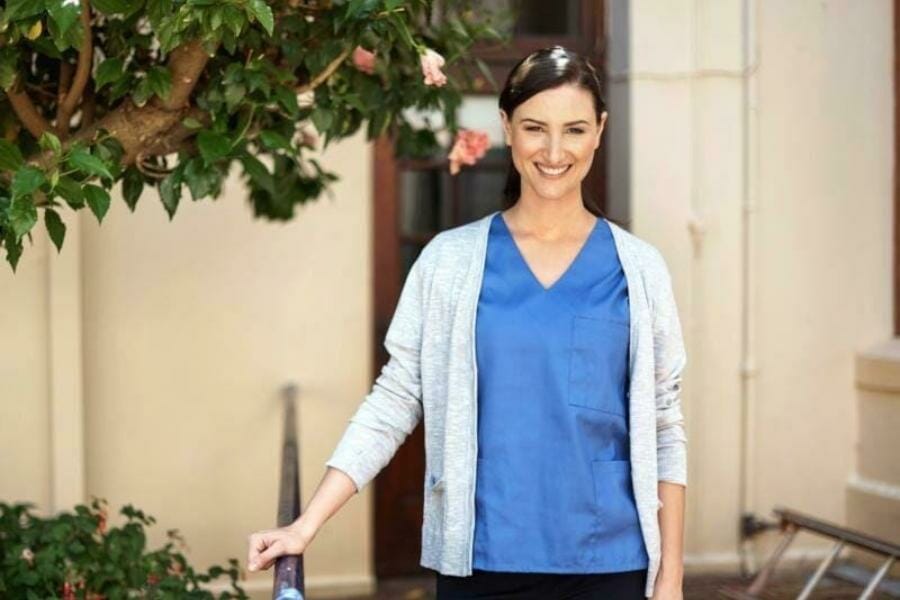 A nurse standing outside smiling