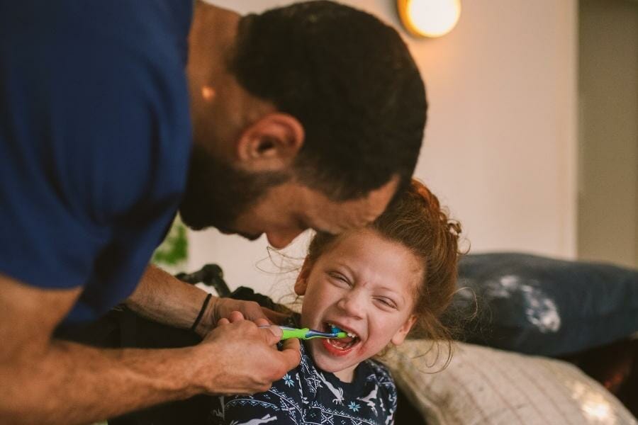 Home pediatric nurse helping his young patient brush their teeth.