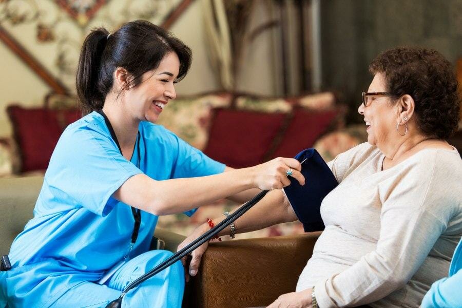 Private nurse checking blood pressure of patient at their home.