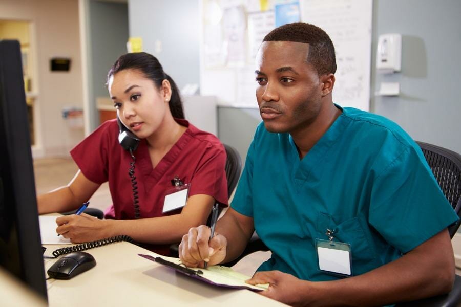 Two nurses at a healthcare facility working on treatment plans.