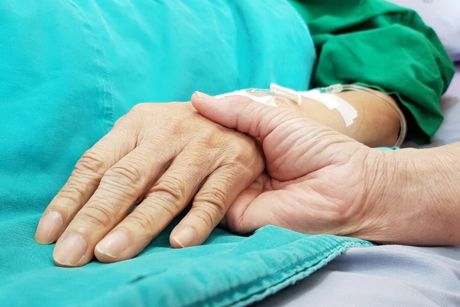 A private nurse holding a seniors hand for emotional support.