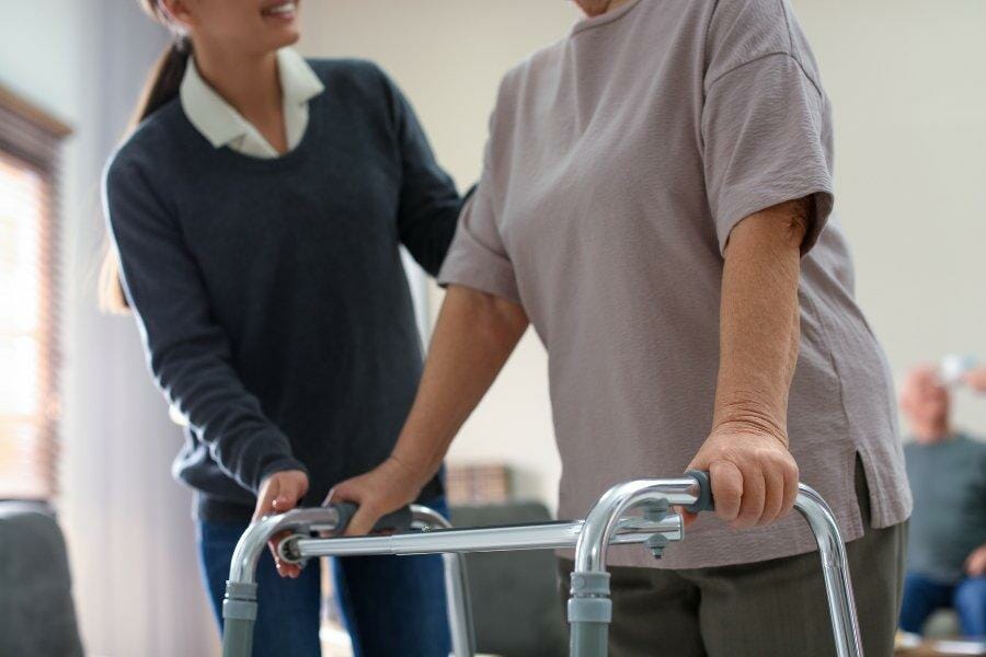 A parkinson's patient with a walker and caregiver.