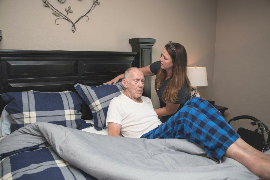 A loved one helping a relative with PD get in bed.