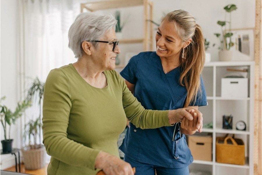 A private duty nurse assisting a patient in walking.