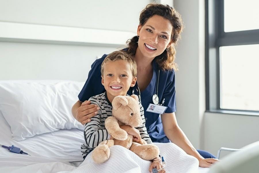 Pediatric nurse and her young client holding a teddy bear.