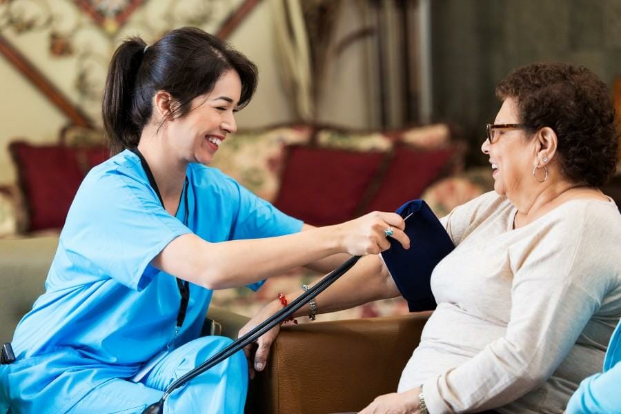 in home nurse checking a client's blood pressure.