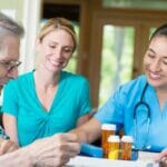 a private duty nurse and home health aid working with a patient.