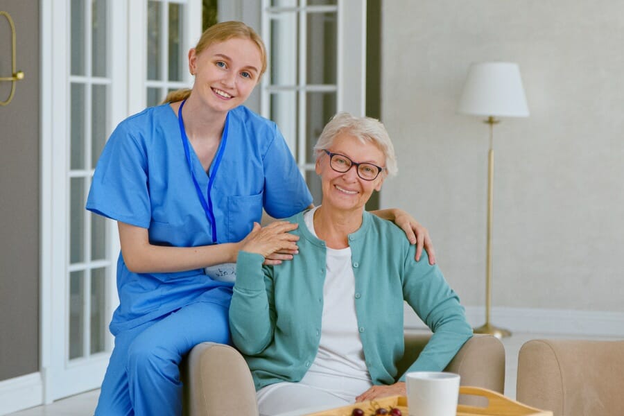 An in home nurse smiling with her client.