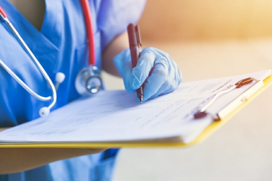 An LVN taking notes on a patient's record