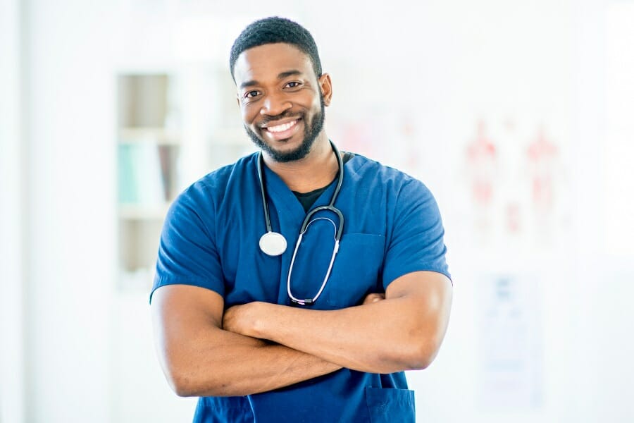 A smiling nurse with his arms crossed