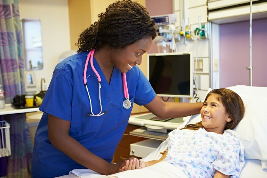 An LVN smiling at her young patient in a medical facility