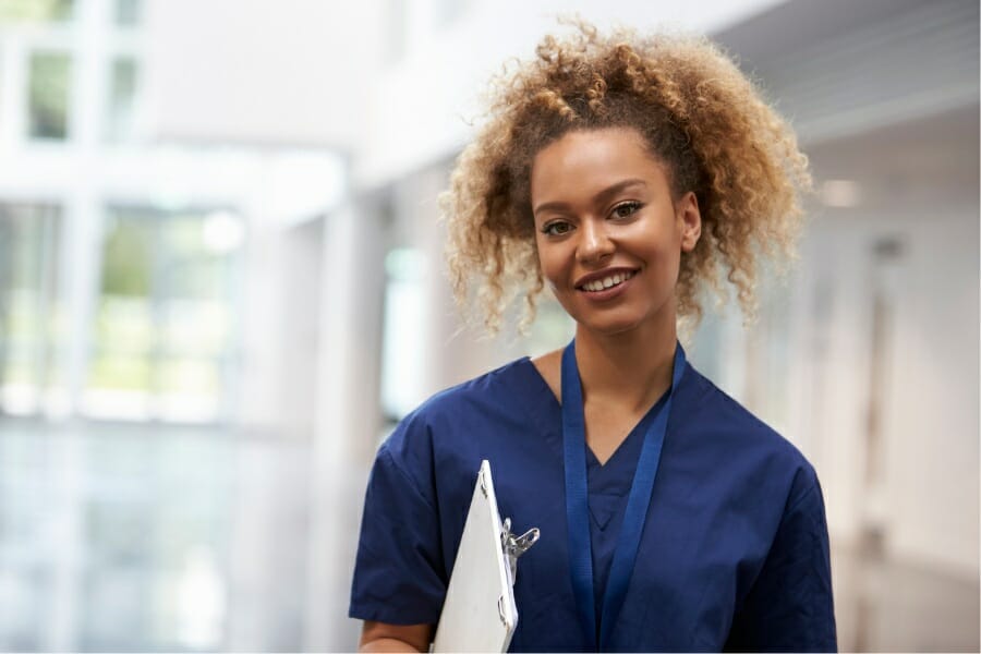 A nurse smiling with her patient's chart in hand.