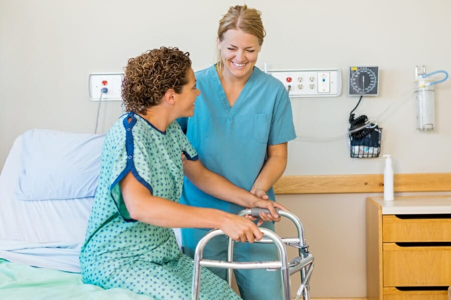 A nurse helping a hospital patient with her walker