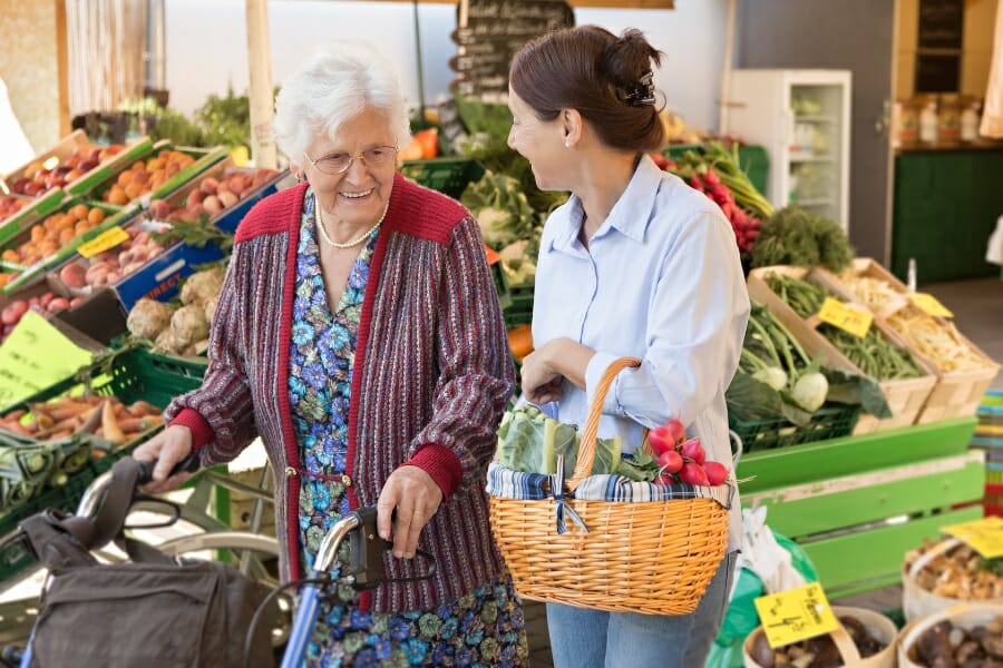 A caregiver helping a senior citizen with her grocery shopping