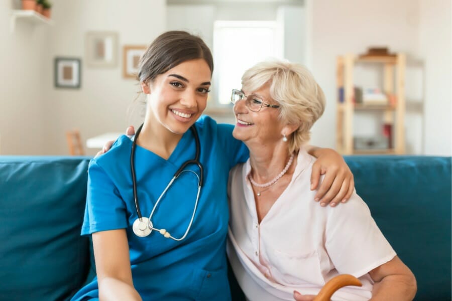 A private duty nurse smiling with her senior patient.