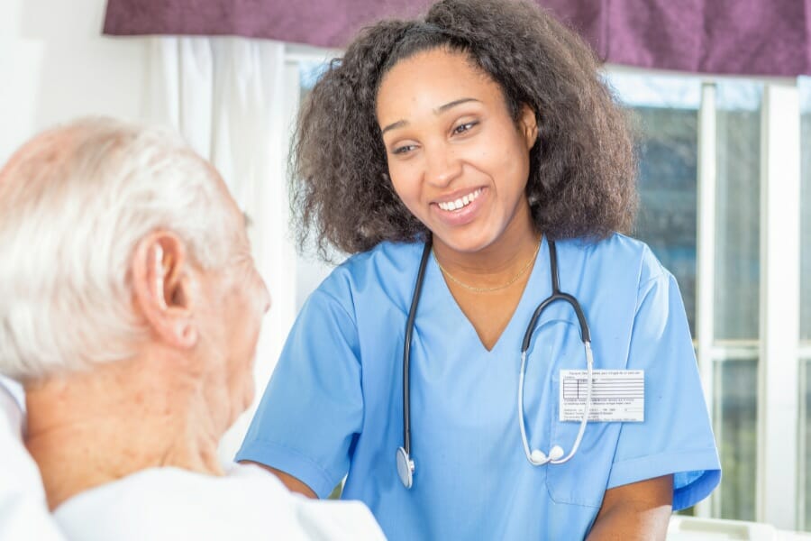 An LVN smiling with an elderly patient