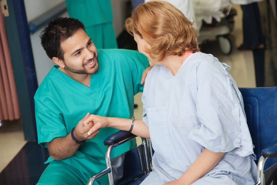 A male nurse assisting a woman in a wheelchair