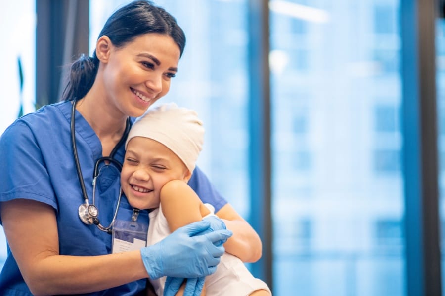 a pediatric nurse hugging a sick child