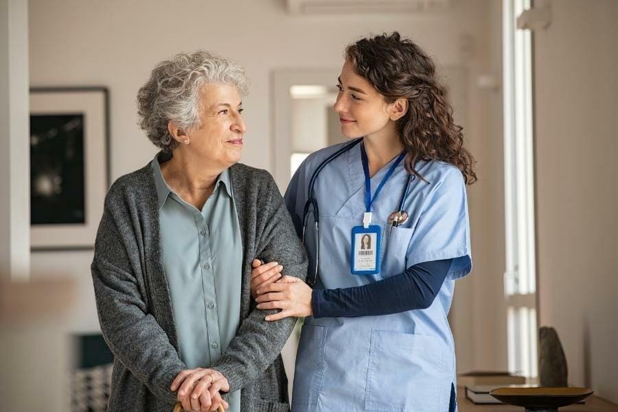 private duty nurse assisting her patient while walking in the living room