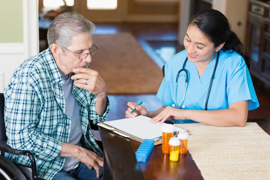 A nurse helping an elderly patient with their medication management