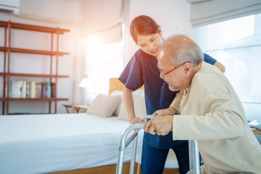 A nurse assisting an older gentleman patient walking